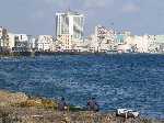 Cuba: Vissers vissen in de zee met op de achtergrond de hoogbouw van hotels in de wijk Vedado langs de MalecÃ³n - Cuba_2005_0017.jpg - Copyright : Ronald van der Veer (http://www.veeronline.nl)